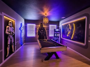 Un tavolo da biliardo in una stanza con arredamento a tema Star Wars, inclusi statue di Stormtrooper e Darth Vader.