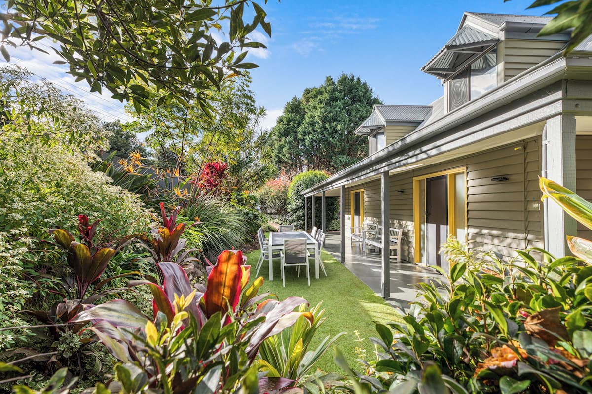 A house with a covered patio, a lawn, and various plants.