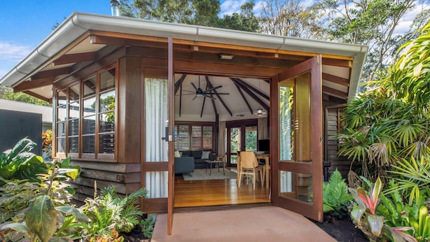 Ein modernes Haus mit überdachter Veranda, großen Fenstern und einem Essbereich.