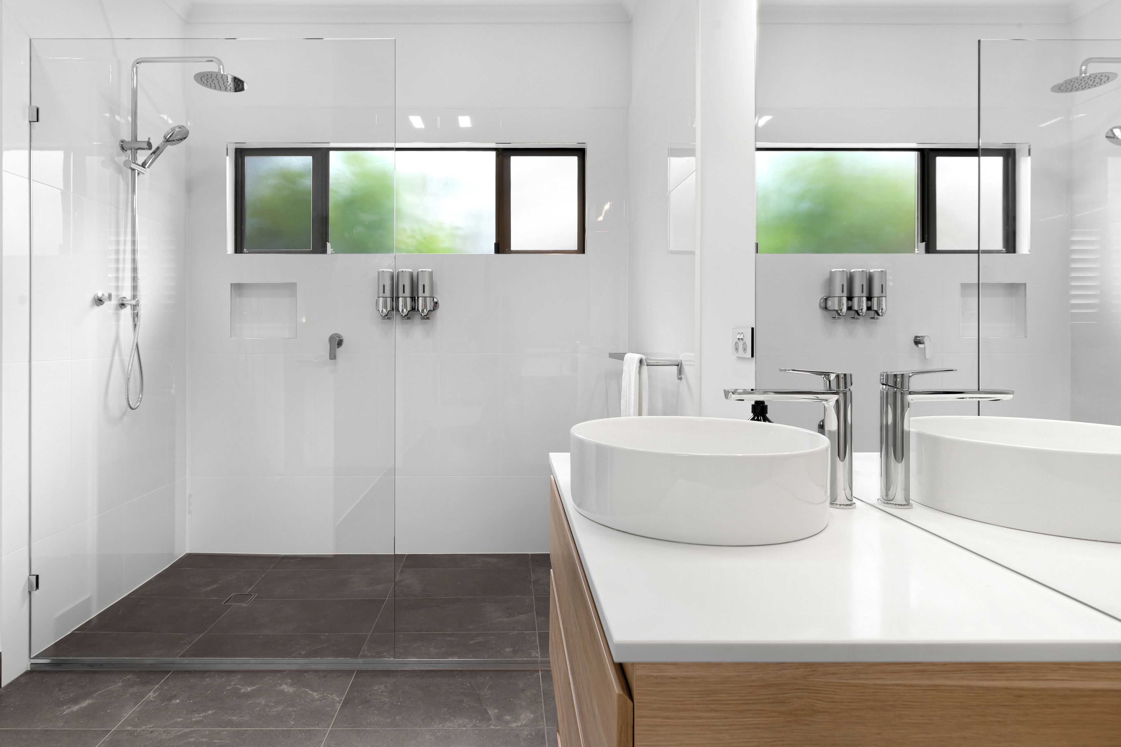 A modern bathroom with a glass-enclosed shower, two sinks, and a large mirror.