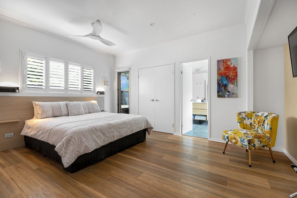 A bedroom with a bed, a chair, and a door leading to a bathroom.