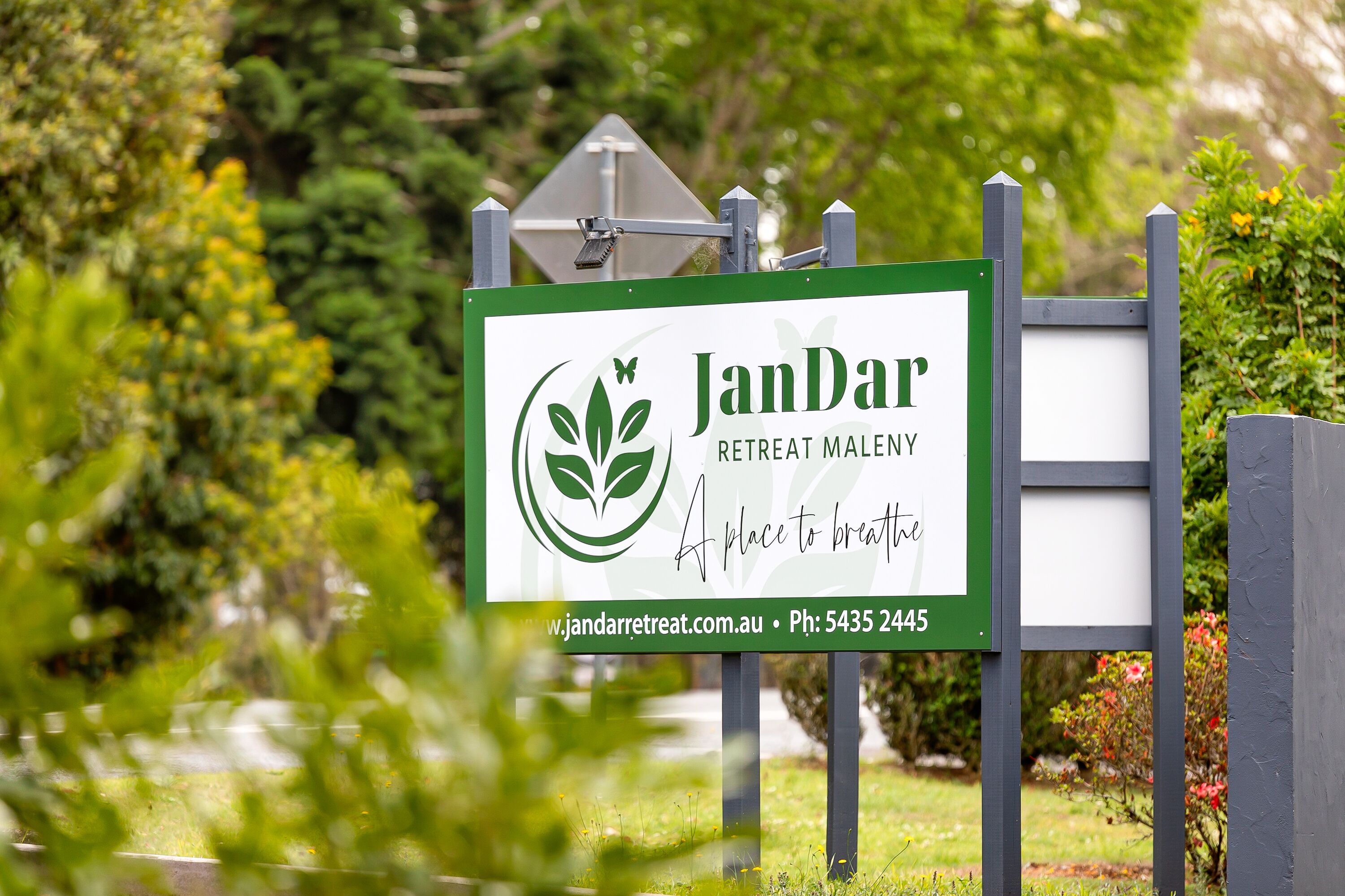 A sign for JanDar Retreat Maleny, featuring a logo and contact information.