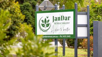 A sign for JanDar Retreat Maleny, featuring a logo and contact information.