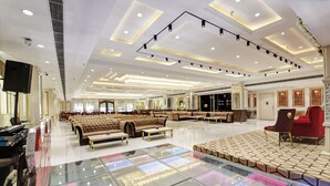 En rummelig hotellobby med et centralt siddeområde, en scene og en glasgulv med LED-lys.