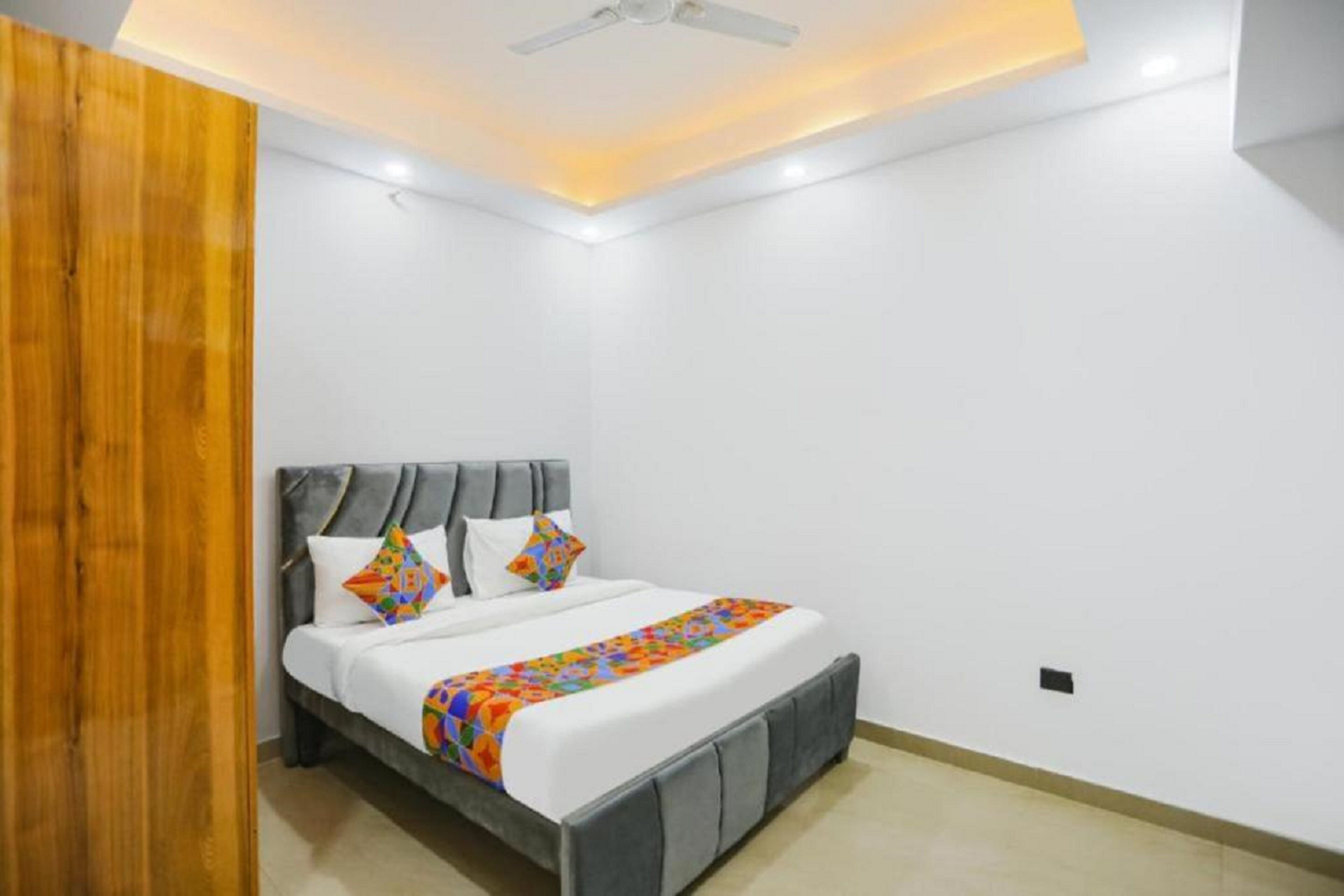 Un dormitorio con una cama, un ventilador de techo y un panel de madera en una pared.