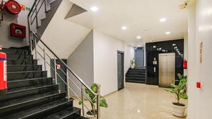 A modern hotel lobby with a staircase, a fire extinguisher, and a potted plant. - Hotel The Rasa Kanti Nagar  (New Delhi)