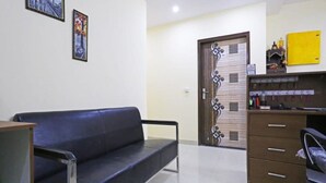 A room with a blue sofa, a wooden cabinet with drawers, and a door with decorative patterns. - Hotel Mannat bhera enclave (New Delhi)