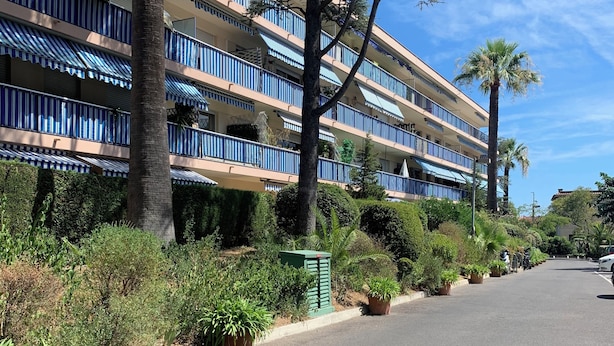 A multi-story hotel with balconies, a palm tree, and a clear sky. - Grand T3 Terrasses Jardin (Antibes)