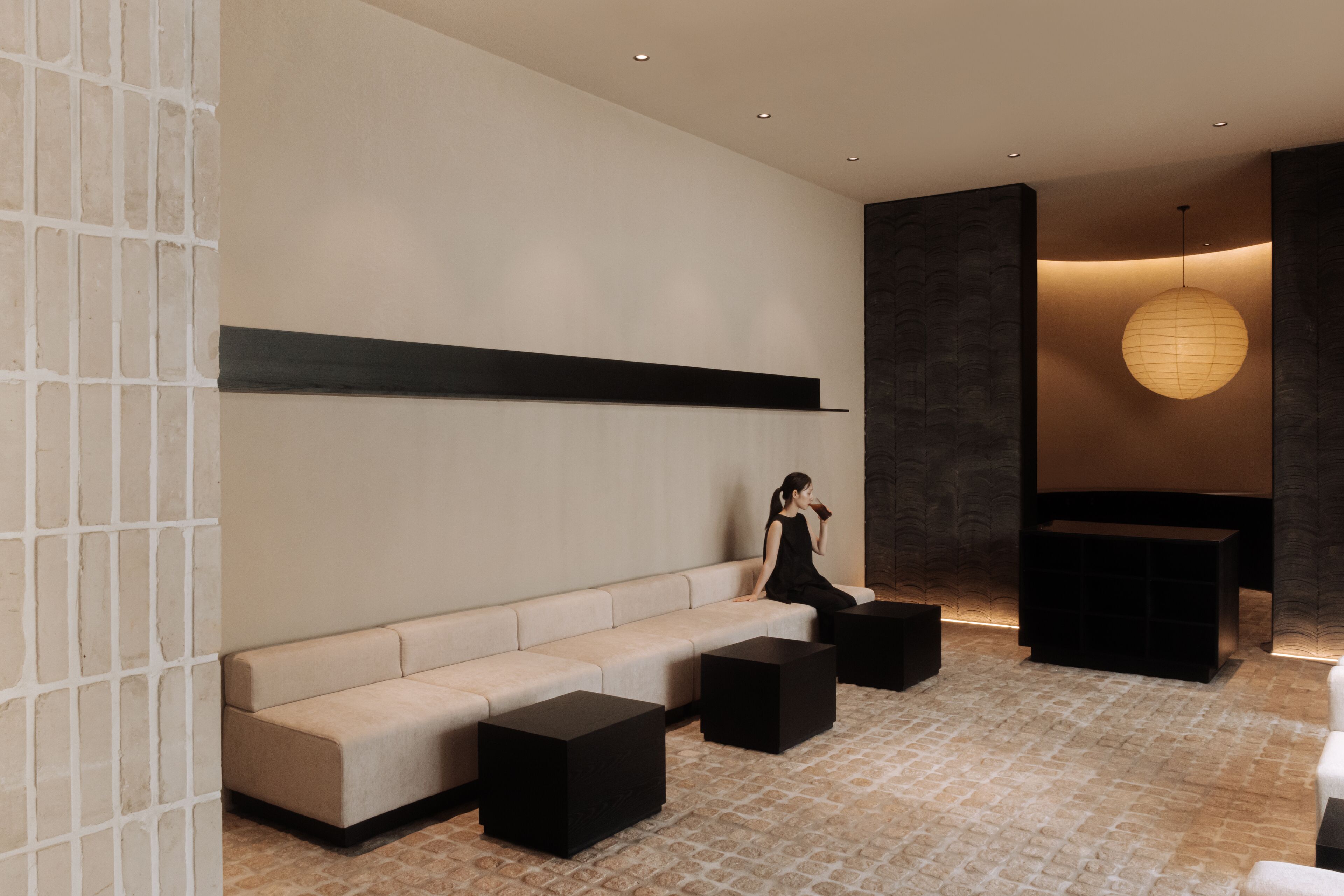 A modern interior with a sofa, black ottomans, and a hanging light fixture.