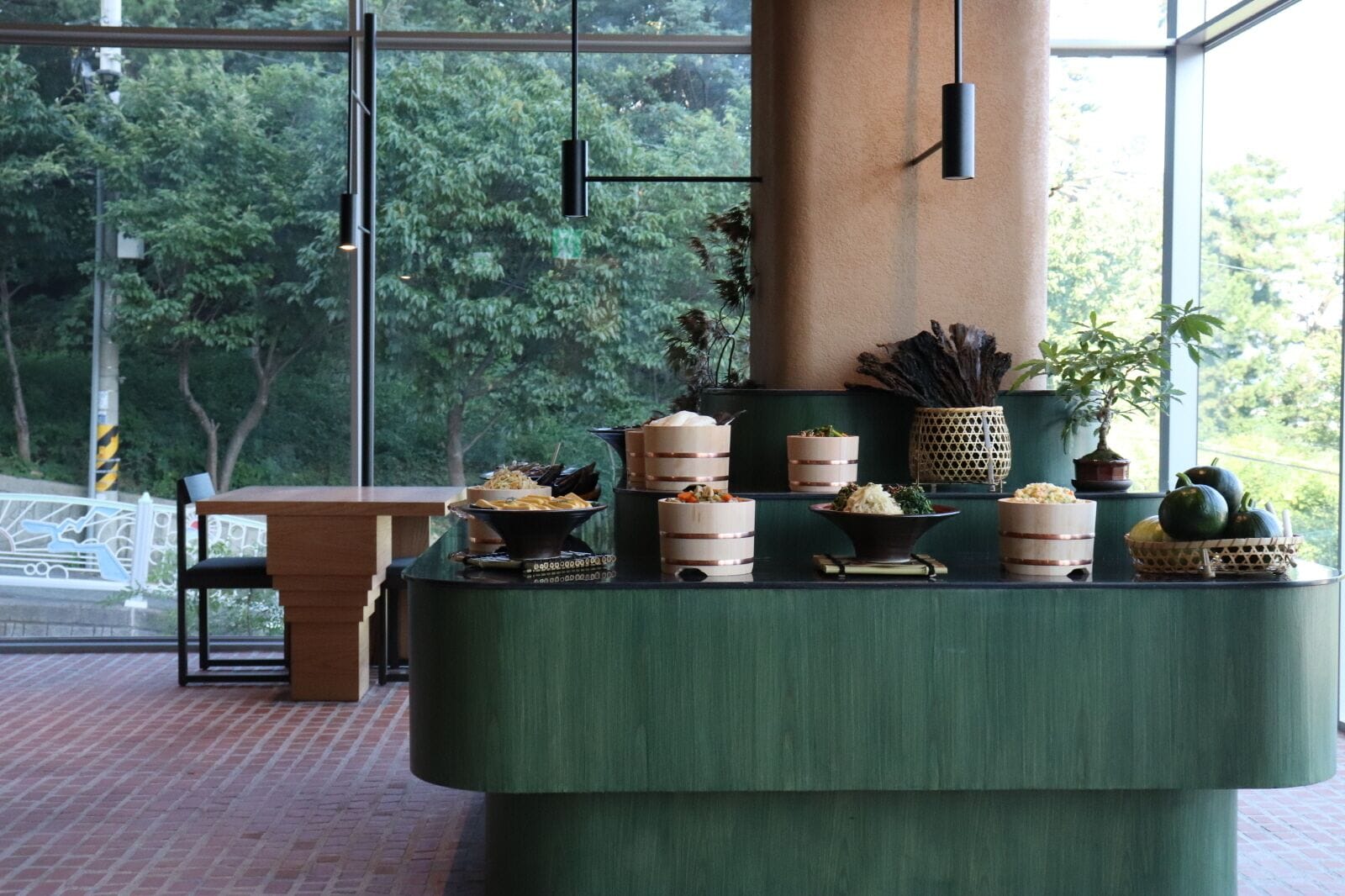 Un comedor con una mesa verde, diferentes platos y plantas en macetas.