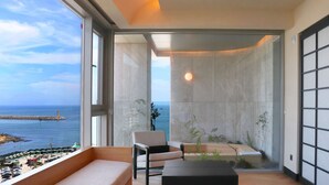 Ein modernes Interieur mit Meerblick, eine Couch, ein Sessel und ein kleiner Tisch.
