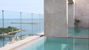Ein moderner Hotelpool mit freiem Blick auf das Meer und eine entfernte Insel.