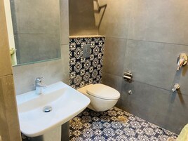 Een kleine badkamer met een wit wastafel, toilet en douche.