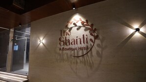 Un mur orné du logo de «The Shanti Boutique Hotel» et d’un élément décoratif rappelant une branche.