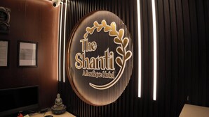 Un comptoir d’accueil avec un panneau circulaire portant l’inscription « The Shanti Boutique Hotel » et une statue de Bouddha.