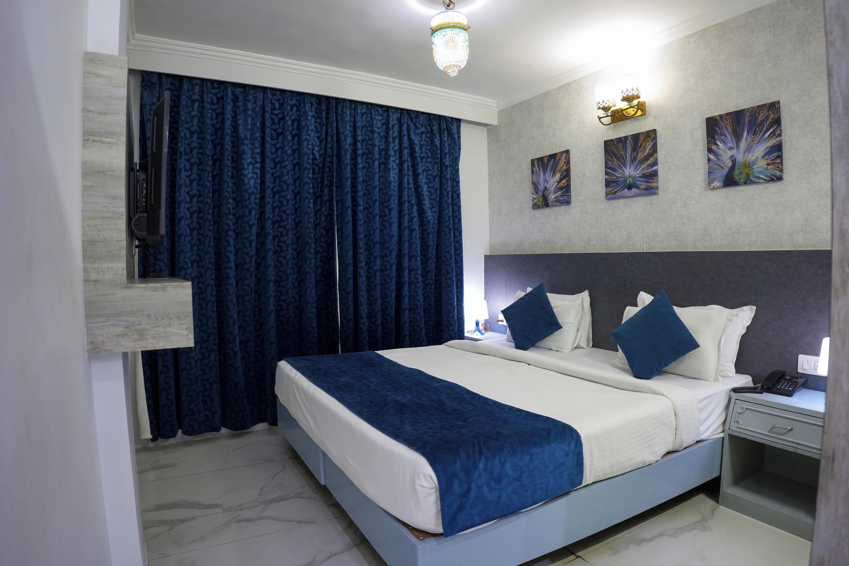 A modern hotel room with a large bed, a nightstand, a desk, and a ceiling light fixture.