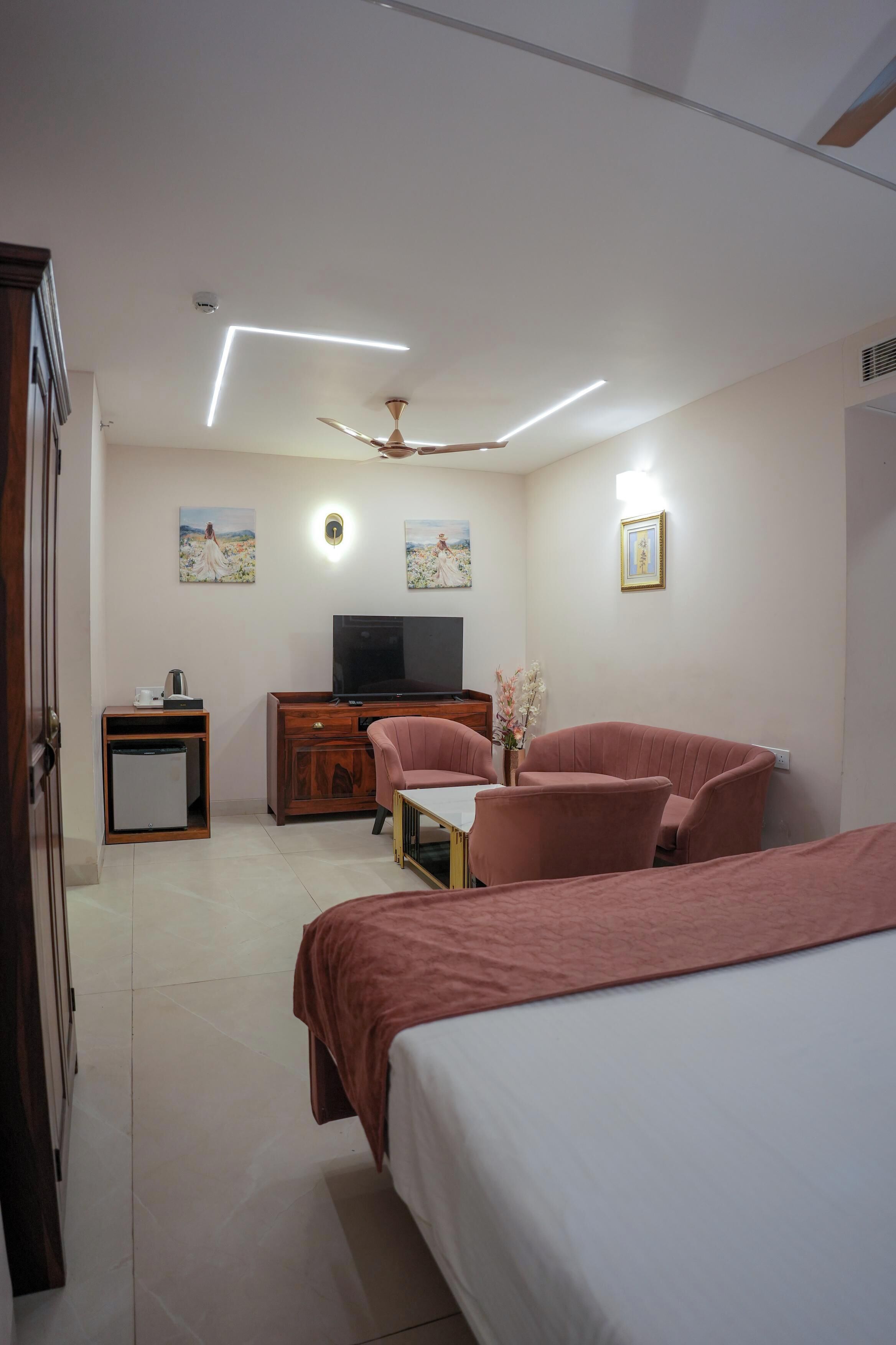 A modern hotel room with a bed, a desk, a television, and a ceiling fan.
