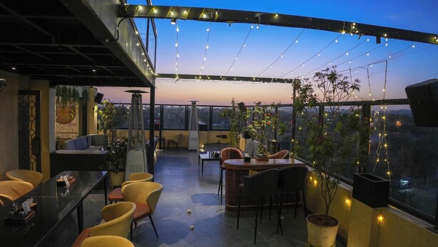 Un espace extérieur aménagé avec des tables, des chaises, des guirlandes lumineuses et des plantes en pot.