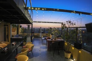 An outdoor seating area with tables and chairs, string lights, and potted plants. - The Shanti A Boutique Hotel (Jodhpur)