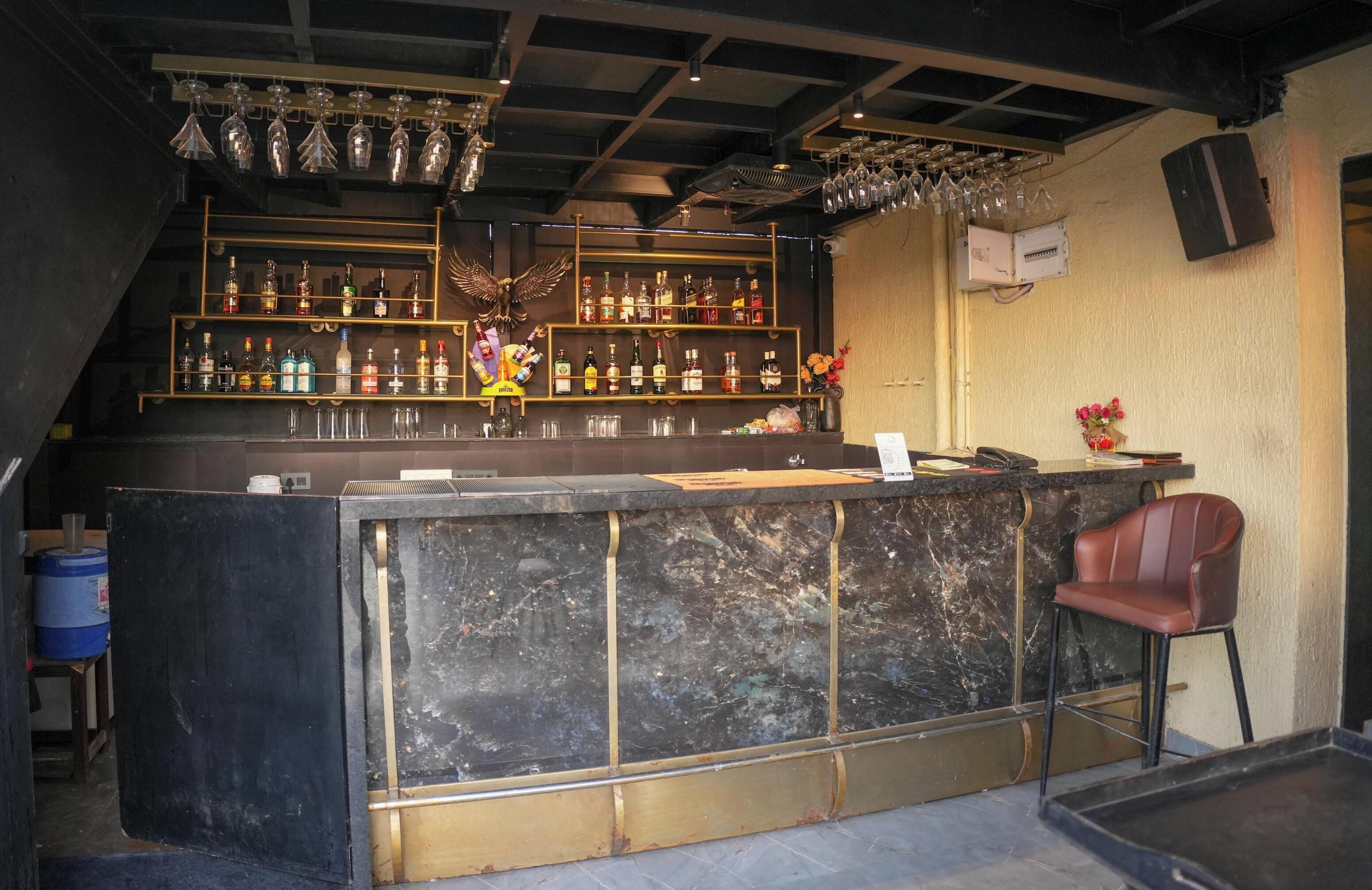 A bar area with a marble counter, shelves of liquor bottles, and a decorative eagle.