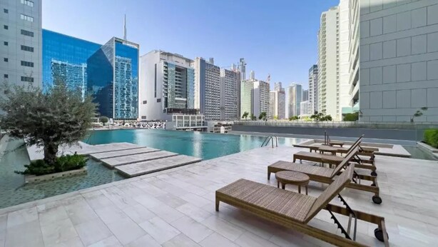 Kattoterassilla on uima-allas, aurinkotuoleja ja sieltä avautuu näkymä moderneihin pilvenpiirtäjiin.
