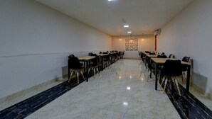 Ein Konferenzraum mit einem langen Tisch, Stühlen, weißen Wänden und einem Fliesenboden.