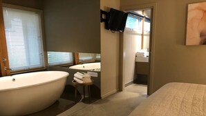 A bathroom with a large bathtub, a sink, and a mirror. - Hepburn Hideaway~ large Villa ~ Hepburn~Daylesford
 (Hepburn Springs)