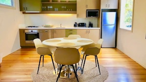 A modern kitchen with a round dining table, chairs, and a built-in microwave. - Hepburn Hideaway~ large Villa ~ Hepburn~Daylesford
 (Hepburn Springs)