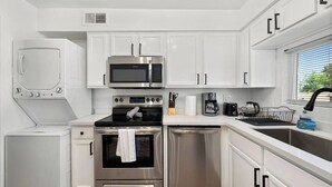 A compact kitchen with white cabinets, a stainless steel microwave, oven, and dishwasher. - King Bed, Pool, Parking, Theme Park, Gym SOON! (Phoenix)