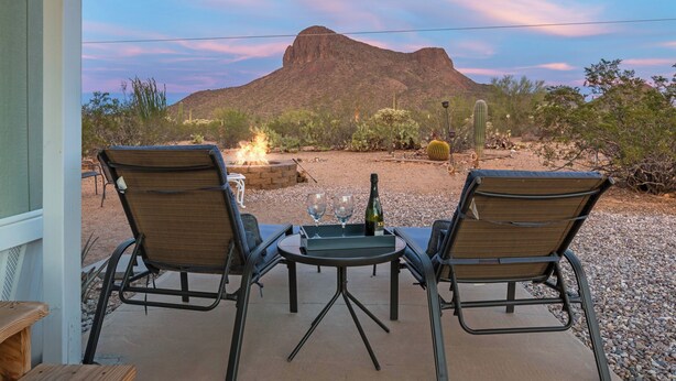 An outdoor patio with two chairs and a table, a fire pit, and a mountain view. - Saguaro Sunset Oasis (Tucson)