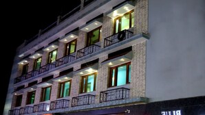 A multi-story hotel with balconies and illuminated windows. - Hotel Apsara By Royal Collection Hotels (Dehradun)