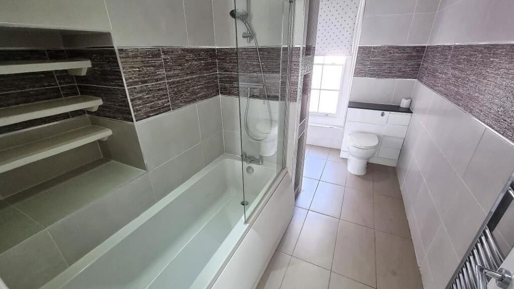 Een badkamer met een douchecabine, een toilet en een wastafel.