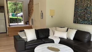 A living room with a black leather sectional sofa, a round marble coffee table, and a white rug. - Lake Daylesford Villa 2~ lake frontage large villa
 (Daylesford)