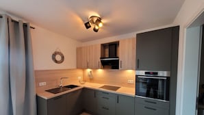 Una cocina moderna con horno empotrado, pileta y muebles de madera.