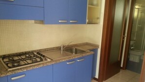 A kitchen with blue cabinets, a granite countertop, a stainless steel sink, and a gas stove. - Apartment With Shared Pool for 4 Guests (San Michele al Tagliamento)