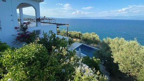 Un bâtiment blanc doté d’un balcon qui offre une vue sur une étendue d’eau et sur des montagnes au loin.