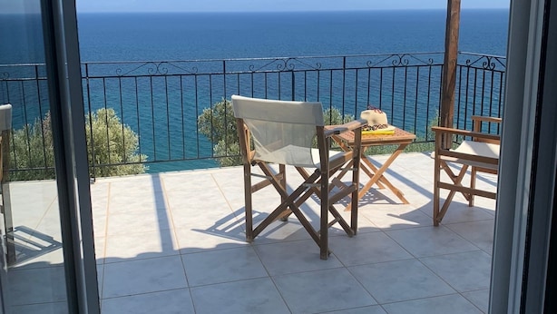 Un balcon avec vue sur la mer, des meubles en bois et un sol carrelé.