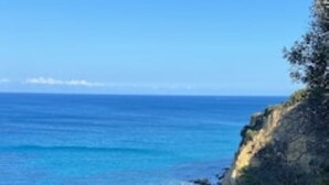 Un paysage côtier caractérisé par des eaux d’un bleu limpide, des affleurements rocheux et une végétation clairsemée.