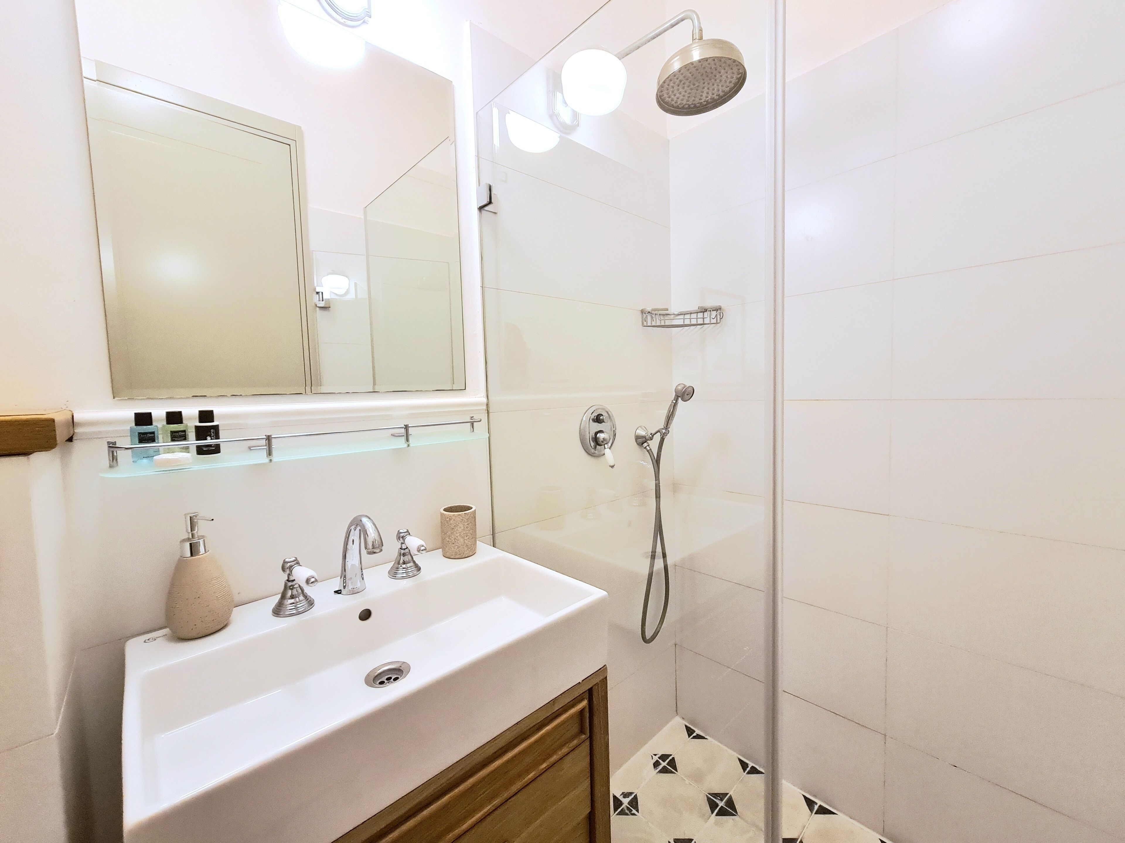 A bathroom with a white sink, mirror, and shower.