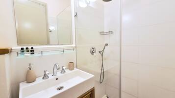 A bathroom with a white sink, mirror, and shower.