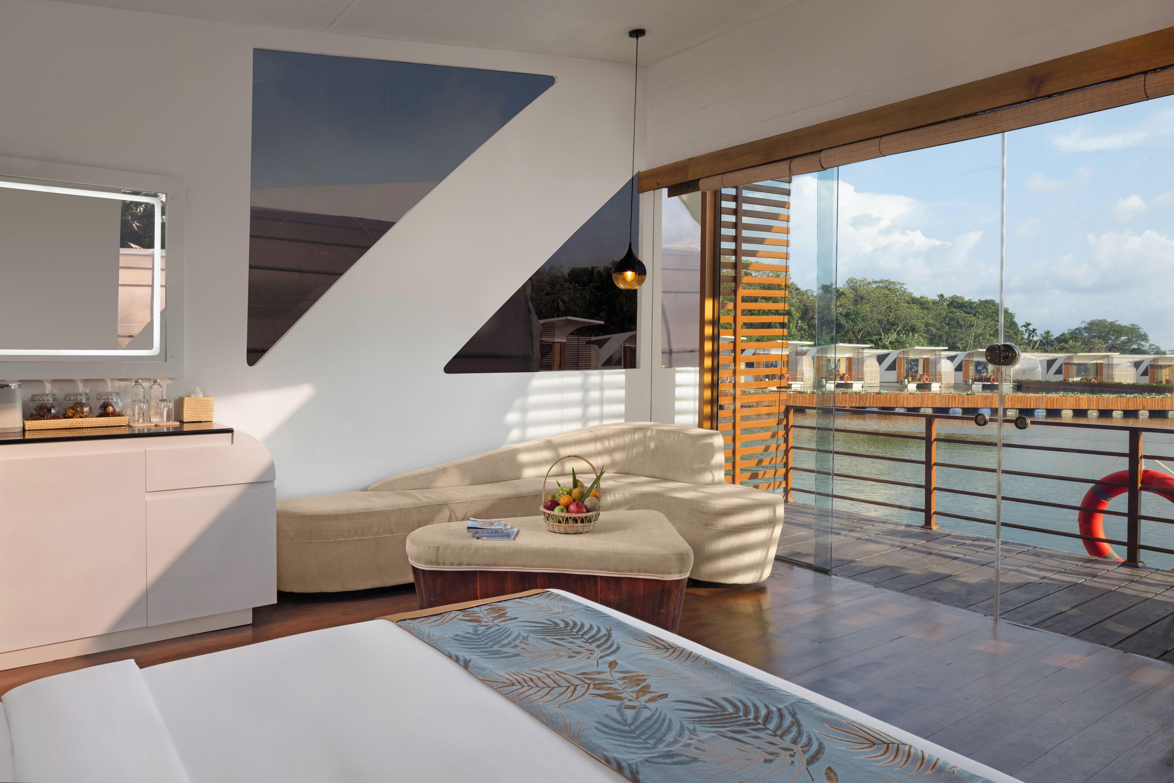 A modern living room with a sofa, a coffee table, and a large window overlooking a body of water.