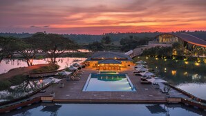 Un espace aménagé au bord de la piscine, avec un bar et des chaises longues, offrant une vue sur un plan d’eau et un coucher de soleil.