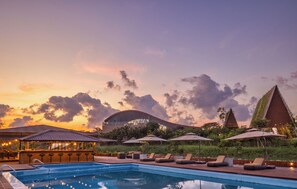 Una piscina al aire libre, sombrillas, sillones reclinables de piscina