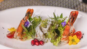 A plate of food with lobster tails, greens, and flowers.