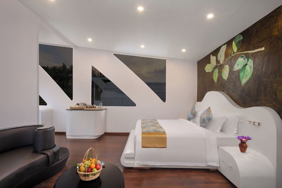 Ein modernes Hotelzimmer mit Bett, Sofa, Essbereich und einem großen Fenster.