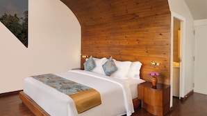 Une chambre à coucher moderne avec un plafond en bois, un grand lit avec une literie à motifs et une table de chevet ornée d’un vase de fleurs.