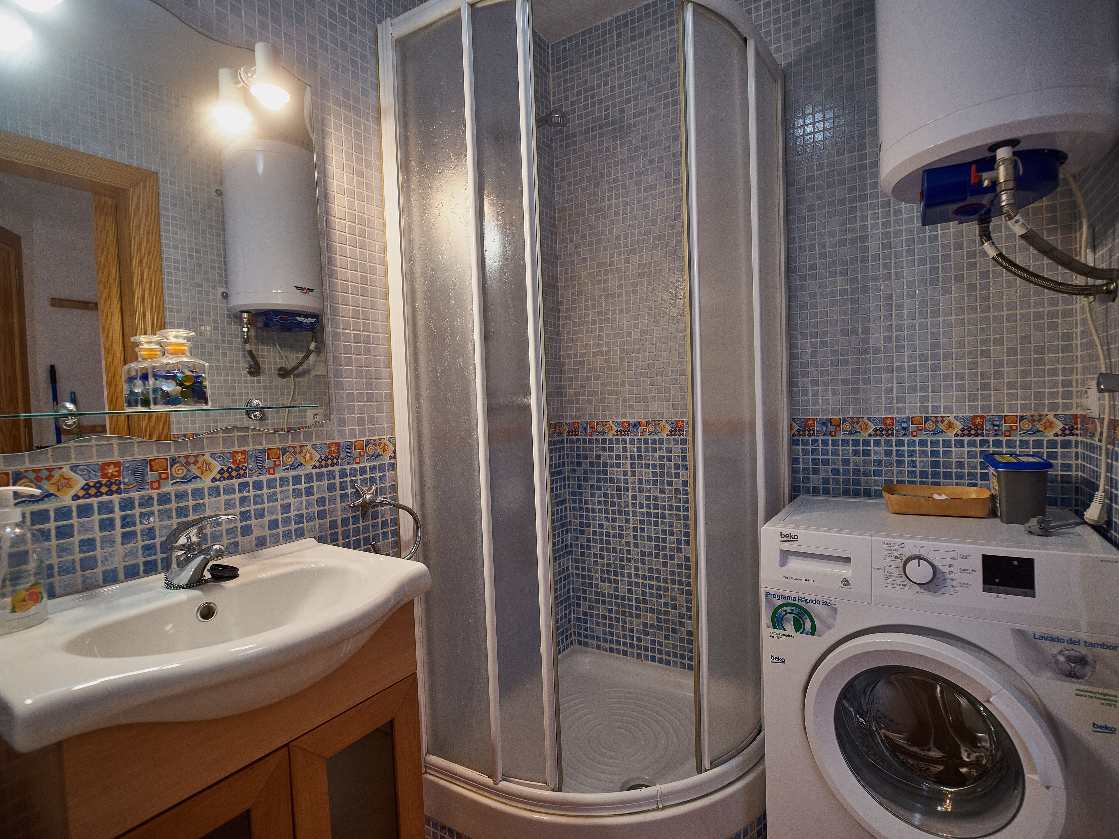 Un bagno con cabina doccia, lavandino e lavatrice.