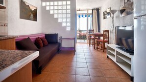 Un salon confortable avec un canapé, un téléviseur et un coin repas.