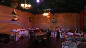 Una habitación tenuemente iluminada con mesas y sillas dispuestas para una reunión.