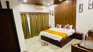 Un dormitorio con cama, cabecera de madera, mesita de noche, escritorio y ventilador de techo.